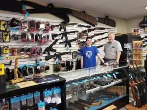 Paul Barnes, right, and his son, Michael, invite customers to their new gun shop in LaGrange